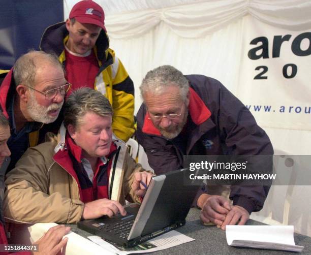 Sir Robin Know-Johnston looks on as competitors in the Around Alone race check out the latest weather reports off a computer, 13 October 2002, at...