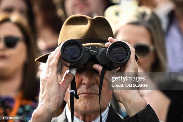 Racegoer watches the race with binoculars during the final day of the Grand National Festival horse race meeting at Aintree Racecourse in Liverpool,...