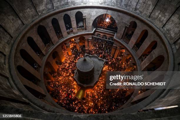 Orthodox Christians gather with lit candles around the Edicule, traditionally believed to be the burial site of Jesus Christ, during the Holy Fire...