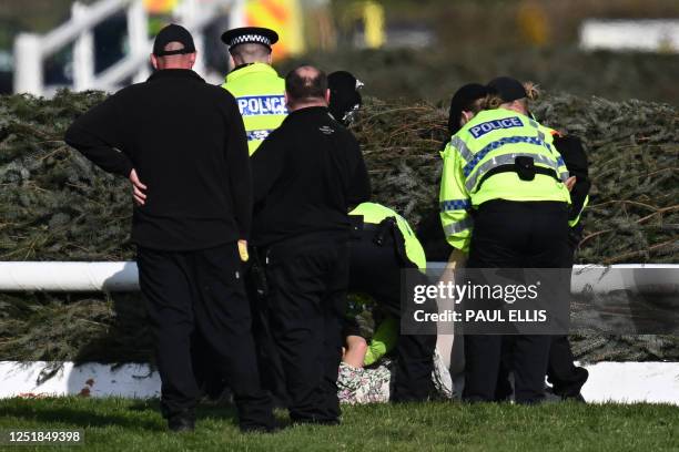 An animal rights protester is apprehended by police officers at the second fence ahead of the Grand National Handicap Steeple Chase on the final day...