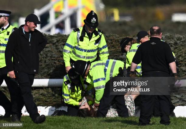 An animal rights protester is apprehended by police officers at the second fence ahead of the Grand National Handicap Steeple Chase on the final day...