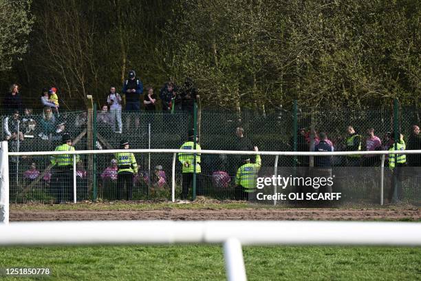 Animal rights protesters are apprehended by police officers behind the fence ahead of the Grand National Handicap Steeple Chase on the final day of...