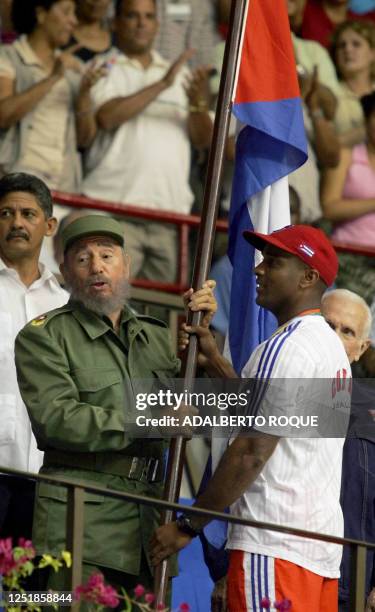 El presidente cubano Fidel Castro recibe en La Habana el 21 de marzo de 2006 de manos de Eduardo Paret , capitan del equipo cubano de beisbol, la...