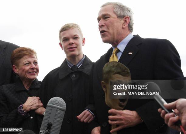 President George W. Bush speaks to the press while holding a cut-out of Jason McElwain as McElwain's mother Debbie watches upon arrival 14 March 2006...