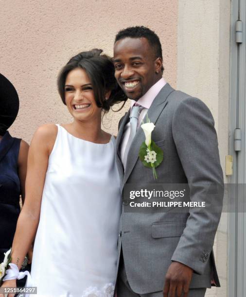 French football player Sidney Govou and his wife Clemence Catherin pose as they leave the church at the end of their wedding ceremony on June 18,...