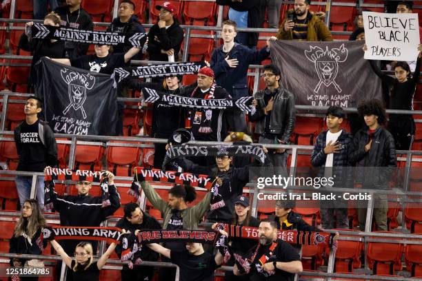 Members of the Viking Army supporters of the New York Red Bulls hold signs of protest saying Believe Black Players while holding scarves that say...