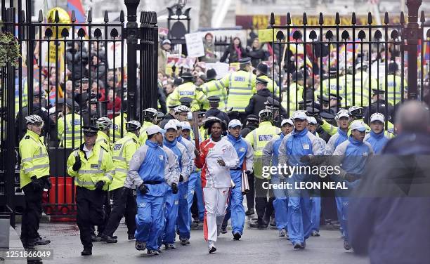 British athlete Denise Lewis carries the Olympic torch amid heavy police protection on April 6, 2008 during her leg of the Beijing Olympics torch...