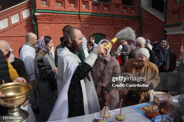 Russian Orthodox Church's priest, Father Mikhail, blesses eggs and cakes during the Easter Orthodox at the Trinity Church, April 15, 2023 in Moscow,...