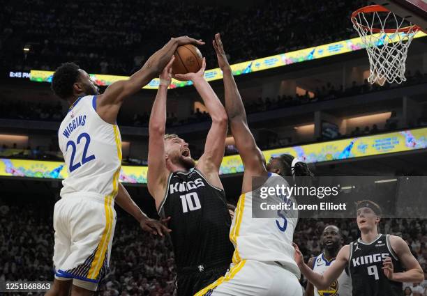 Domantas Sabonis of the Sacramento Kings looks to shoot as Andrew Wiggins and Kevon Looney of the Golden State Warriors defend during the second...