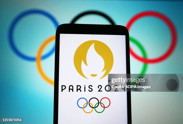 In this photo illustration, 2024 Summer Olympics logo is seen on a smartphone and Olympic rings on a pc screen.