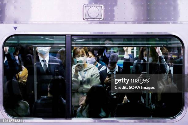 People are traveling inside the crowded train of the Yamanote Line at JR Tokyo Station.