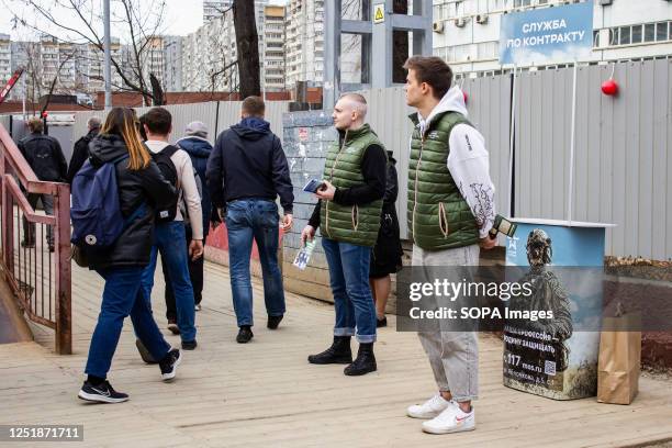 Two volunteers operate a mobile army recruitment spot set up on a crowded path near a train stop in Moscow, Russia. They distribute leaflets and...