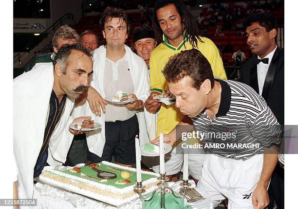 Tennis player Gene Mayer blows out the candles on his birthday cake 12 April in the presence of Frenchmen Yannick Noah and Henri Leconte and Iranian...