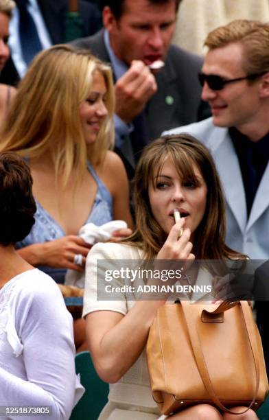 British supermodel Liz Hurley does her lipstick while Russian tennis star Anna Kournikova chats with her boyfriend during a charity tennis match in...