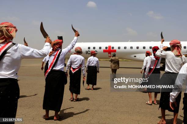 Men dressed in traditional Yemeni outfits raise their daggers upon the landing of an aircraft of the International Committee of the Red Cross...