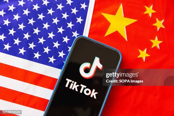 In this photo illustration, a mobile phone displays TikTok logo with the flags of United States of America and People's Republic of China in the...