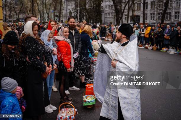 An Orthodox priest splashes holy water on worshippers during the celebration of the Orthodox Easter outside Saint Volodymyr's Cathedral in Kyiv on...