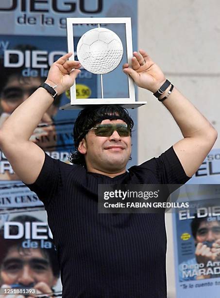 Ex-soccer player Diego Maradona exhibits in Buenos Aires 22 December 2000, the trophy for the best player of the world according to a survey made by...