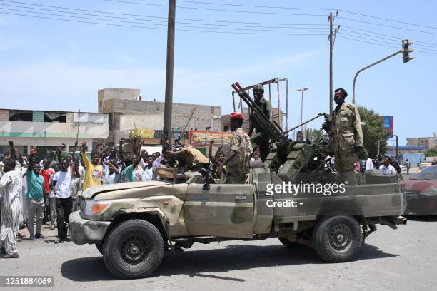 Sudanese greet army soldiers, loyal to army chief Abdel Fattah al-Burhan, in the Red Sea city of Port Sudan on April 16, 2023. Battling fighters in...