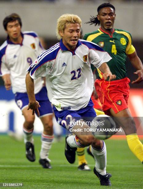 Japan's Takayuki Suzuki runs with the ball as Cameroon defender Rigobert Song watches during their Confederations Cup match in Niigata, 02 June 2001....