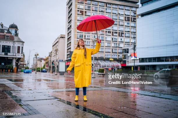 cheerful woman with red umbrella - female rain coat stock pictures, royalty-free photos & images
