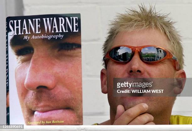 Australian spinner Shane Warne watches proceedings from the team's balcony with a copy of his autobiography on the second day of the third Test Match...