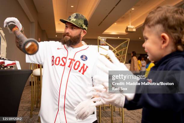 Former Boston Red Sox player Jonny Gomes shows his son his bat from the Baseball Hall of Fame during a game between the Los Angeles Angels and the...