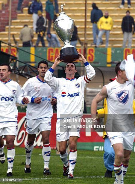 The captain of Club Nacional of soccer, Alejandro Lembo lifts the trophy of Apertura Tournament, while he does the olympic run next to his teammate,1...