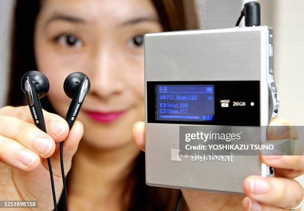Japan's electronics giant Toshiba employee Midori Suzuki displays the world's smallest and lightest harddisk audio player "gigabeat G20" equipped...