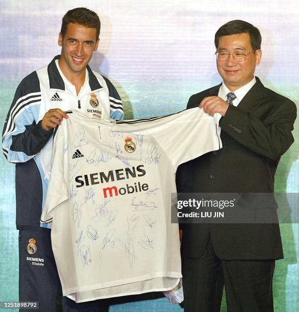 Spanish football star and Real Madrid team leader Raul Gonzalez presents a uniform full of players' autographs to Zhang Zhenguo, the mayor of...