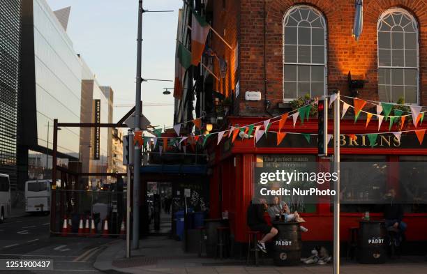 People relax in an Irish pub with flags of the national flag of Ireland in Dublin. Ireland, Sunday, April 16, 2023.