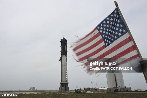 Flag waves in the wind as the SpaceX Starship stands on the launch pad ahead of a flight test from Starbase in Boca Chica, Texas on April 16, 2023. -...