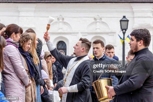 Priest blesses Ukrainian believers with Holy Water as they attend the Easter Sunday traditional celebration in St. Michael's Golden-Domed Monastery...