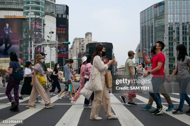 This picture taken on April 14, 2023 shows people walking down a street at the Ximen district in Taipei. - At a barbed-wire Taipei museum where...