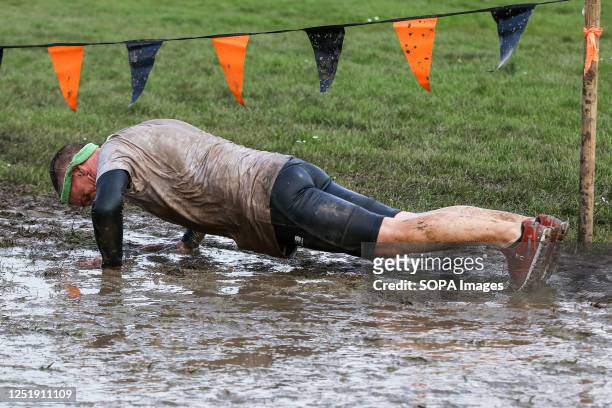 Participant does press-ups during Tough Mudder race in Finsbury Park, London. Tough Mudder was co-founded by Will Dean and Guy Livingstone and the...