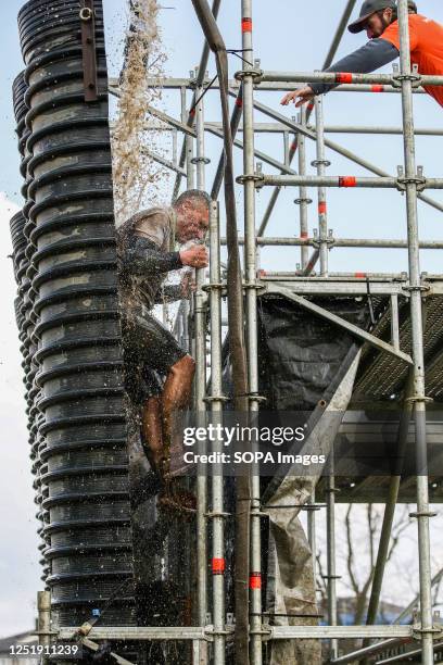 Participant climbs as water falls on him during the Tough Mudder race in Finsbury Park, London. Tough Mudder was co-founded by Will Dean and Guy...