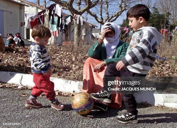 Des enfants jouent sous la surveillance de leur grand-mère, le 22 février 2001 dans le camp militaire de Fréjus, alors que leurs parents, des...