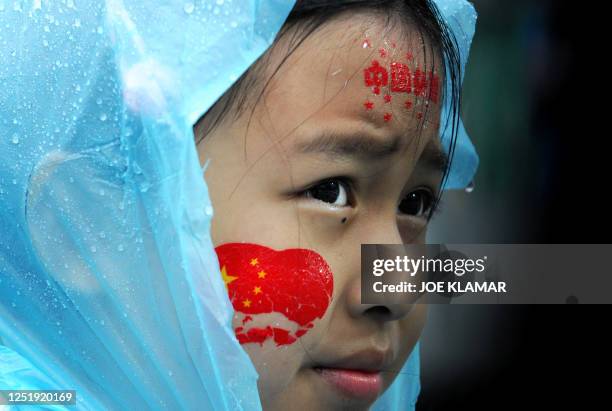 Chinese fan watches a beach volleyball match between China and Spain in the pouring rain at Beijing's Chaoyang Park Beach Volleyball Ground on August...