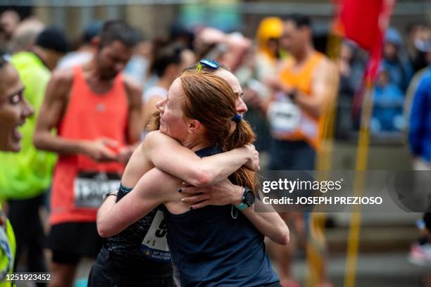 Runners embrace in the cool off area during the 127th Boston Marathon in Boston, Massachusetts on April 17, 2023. - In wet and windy conditions, 2022...