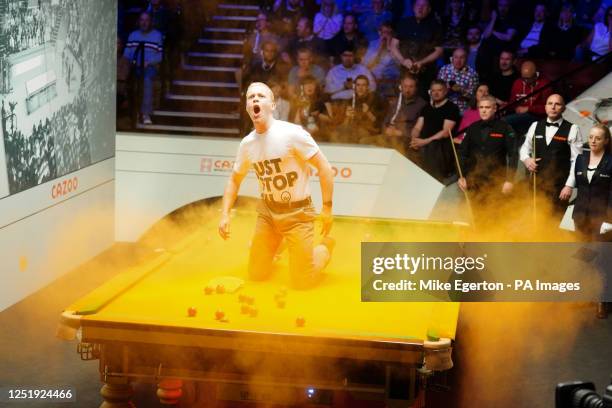 Just Stop Oil protester jumps on the table and throws orange powder during the match between Robert Milkins against Joe Perry during day three of the...