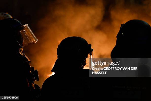 French CRS riot police stand in front of a fire following a concert of pans to protest during French President Emmanuel Macron's televised address to...