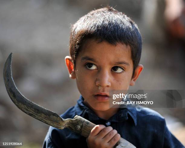 An Afghan child holding a farming tool looks on as soldiers from A Company of the 1st Battalion Royal Gurkha Rifles patrol near Nahr e Saraj village,...