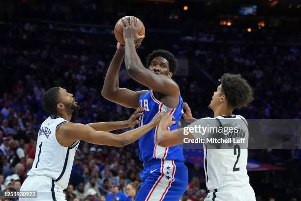 Joel Embiid of the Philadelphia 76ers controls the ball against Mikal Bridges and Cameron Johnson of the Brooklyn Nets in the first quarter during...