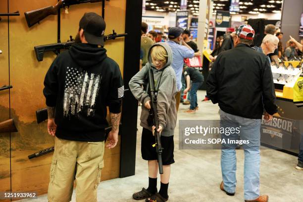 Boy holds a rifle during the National Rifle Association's Annual Meetings & Exhibits at the Indiana Convention Center in Indianapolis. The convention...