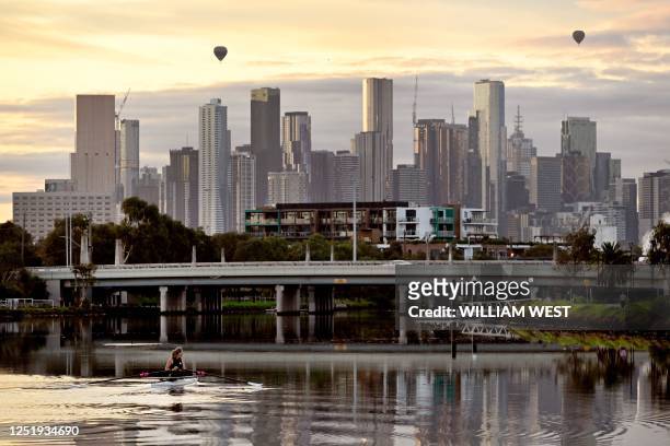 Rower makes their way along the Maribyrnong River towards the Melbourne skyline in the early morning light on April 18, 2023. - Melbourne has...