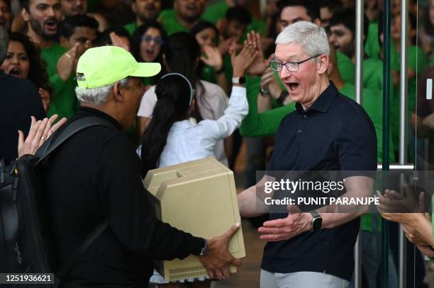 Chief Executive Officer of Apple Tim Cook reacts as a man shows him a Macintosh SE computer during the opening of Apple's first retail store in...