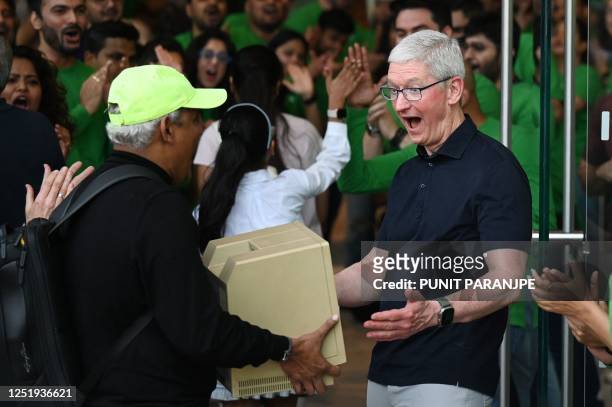Chief Executive Officer of Apple Tim Cook reacts as a man shows him a Macintosh SE computer during the opening of Apple's first retail store in...