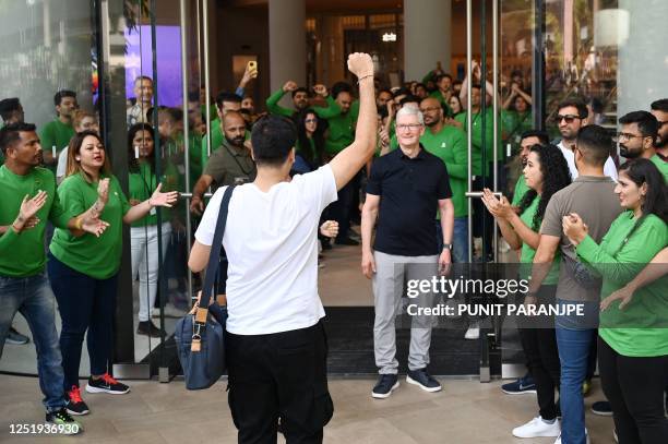 Chief Executive Officer of Apple Tim Cook looks on next to Apple employees cheering as a customer enters Apple's first retail store in India during...