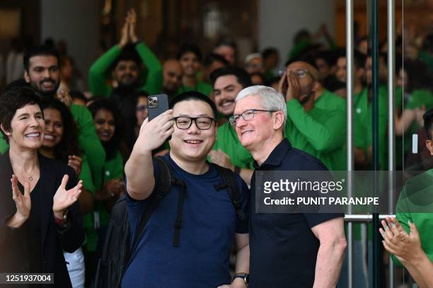 Chief Executive Officer of Apple Tim Cook poses for a selfie with a man during the opening of Apple's first retail store in India, in Mumbai on April...