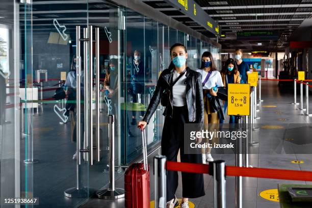 passengers wearing n95 face masks waiting in line at airport terminal - airport stock pictures, royalty-free photos & images